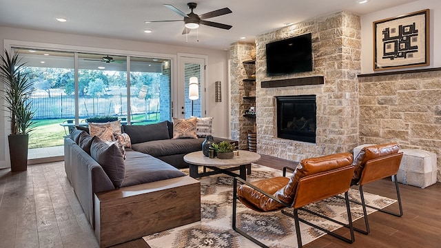 living room featuring ceiling fan, a stone fireplace, and hardwood / wood-style floors