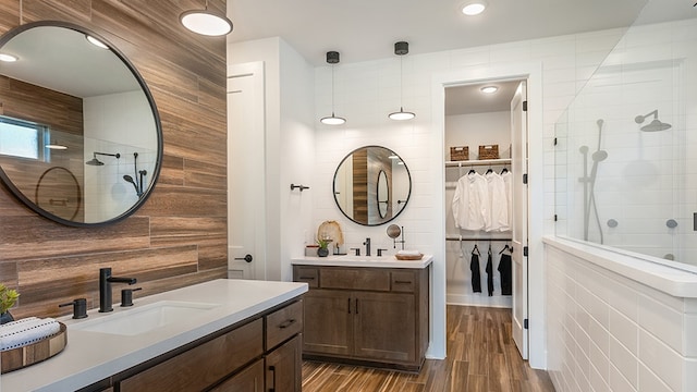 bathroom with hardwood / wood-style floors, a tile shower, tile walls, and vanity