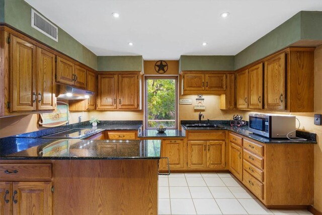 kitchen featuring light tile patterned floors, sink, black electric stovetop, kitchen peninsula, and dark stone counters