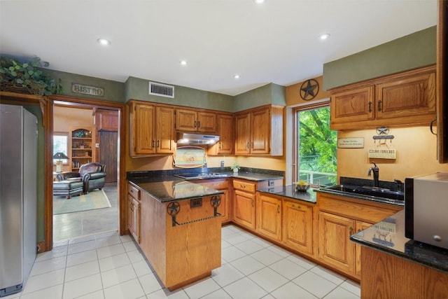 kitchen featuring sink, dark stone counters, light tile patterned floors, kitchen peninsula, and stainless steel appliances