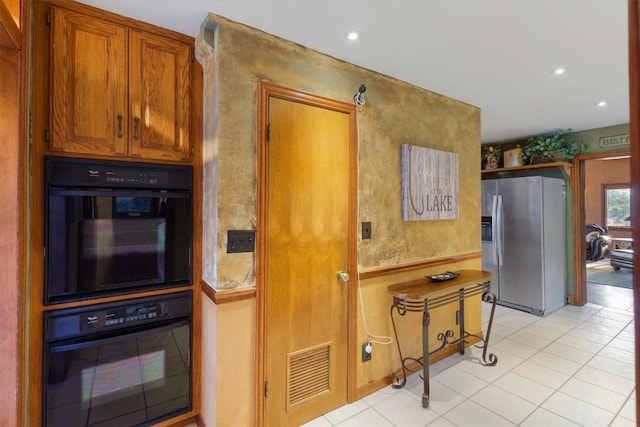 kitchen with light tile patterned floors, stainless steel fridge, and double oven