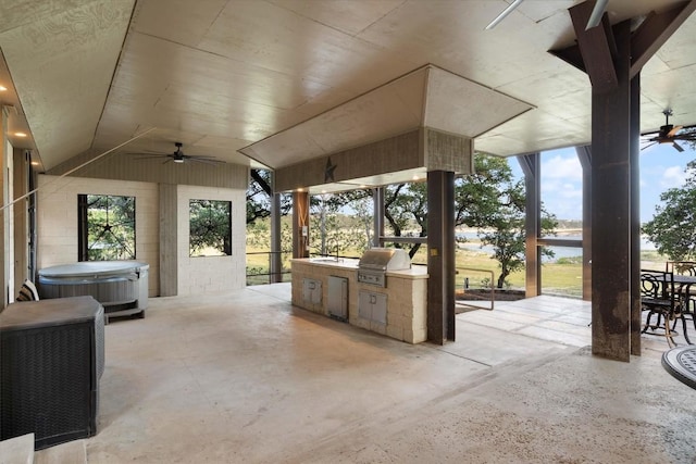 view of patio with area for grilling, a water view, ceiling fan, and exterior kitchen