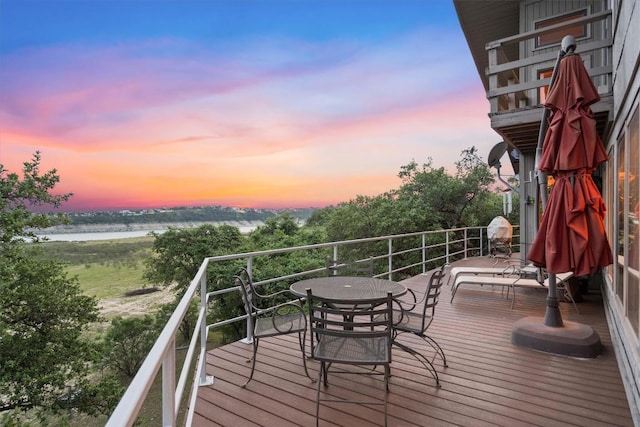 deck at dusk featuring a water view