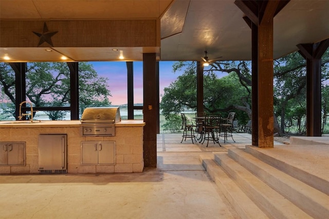 view of patio featuring outdoor dining space, a sink, and area for grilling