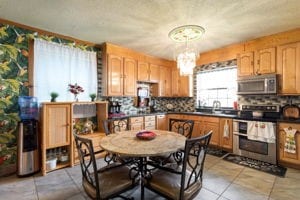 kitchen with stainless steel appliances, light tile patterned flooring, hanging light fixtures, a chandelier, and backsplash