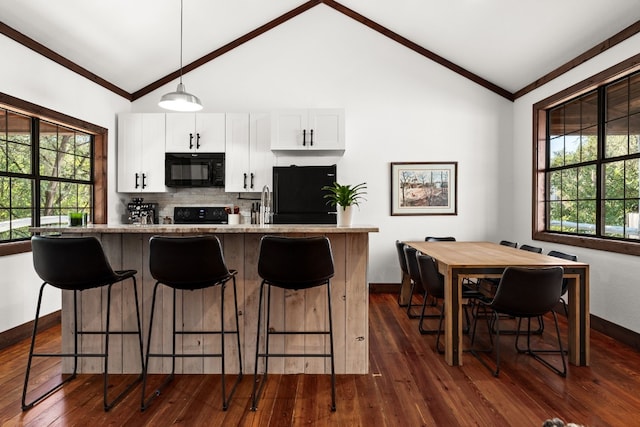 kitchen featuring light stone countertops, black appliances, white cabinets, dark hardwood / wood-style flooring, and hanging light fixtures