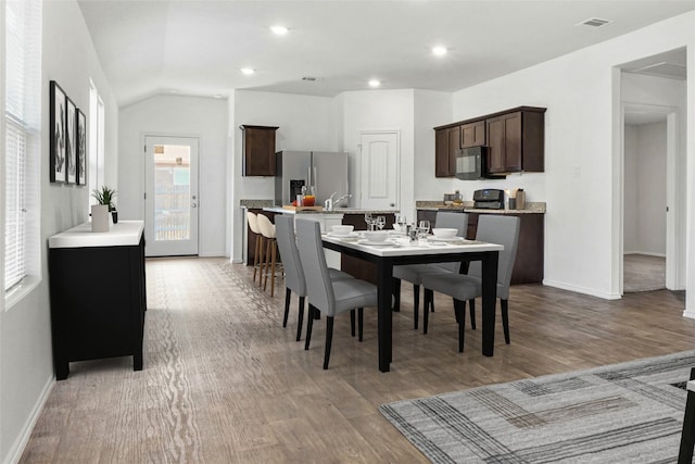 dining room with lofted ceiling, sink, and wood-type flooring