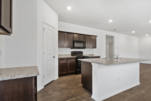 kitchen with black appliances, dark brown cabinetry, dark wood-type flooring, sink, and a center island with sink