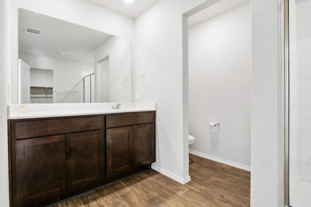 bathroom with vanity, walk in shower, toilet, and wood-type flooring