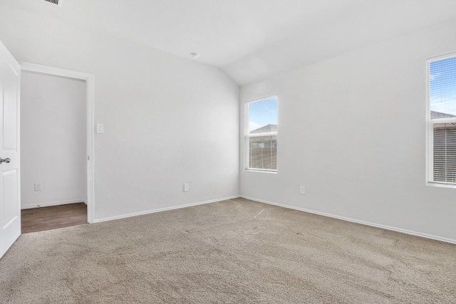 carpeted empty room with lofted ceiling and plenty of natural light