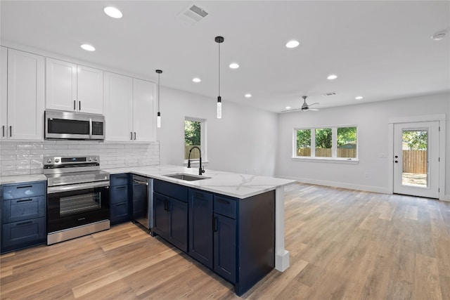 kitchen with white cabinets, sink, kitchen peninsula, pendant lighting, and appliances with stainless steel finishes