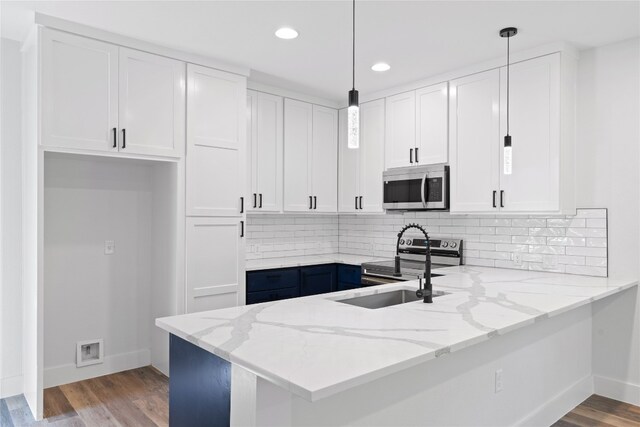 kitchen featuring stainless steel appliances, hanging light fixtures, light hardwood / wood-style floors, and white cabinetry