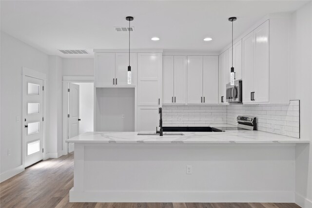 kitchen featuring white cabinets, kitchen peninsula, decorative light fixtures, appliances with stainless steel finishes, and light stone countertops