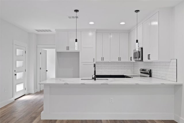 909 Vargas Rd Unit B, Austin, TX 78741 - kitchen with light stone countertops, stainless steel appliances, a peninsula, and visible vents
