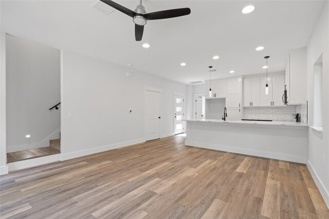 unfurnished living room featuring light wood-type flooring, ceiling fan, and sink