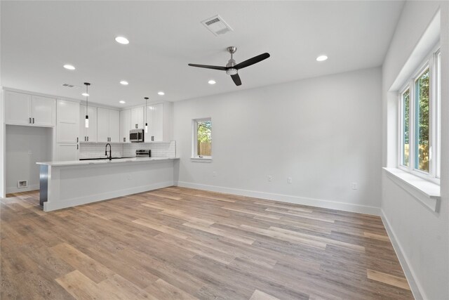 kitchen featuring kitchen peninsula, a healthy amount of sunlight, decorative light fixtures, and white cabinetry