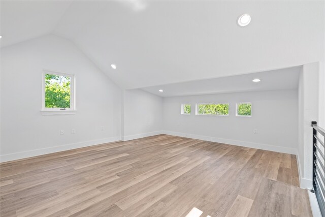 additional living space featuring lofted ceiling, a healthy amount of sunlight, and light hardwood / wood-style floors