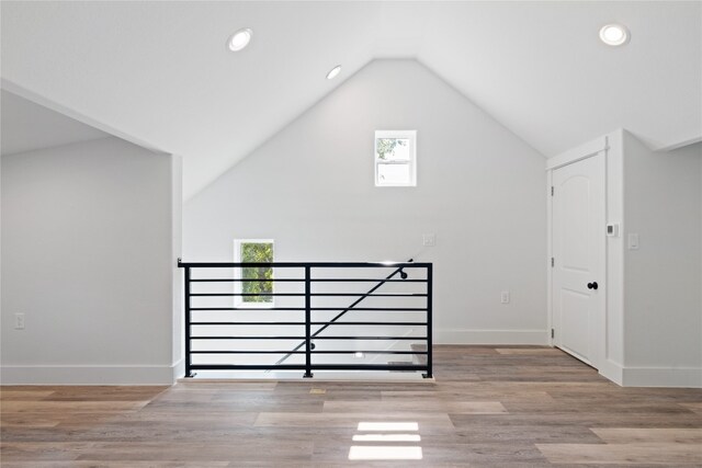 additional living space with lofted ceiling, light wood-type flooring, and a healthy amount of sunlight