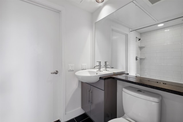 bathroom with tile patterned flooring, a tile shower, vanity, and toilet