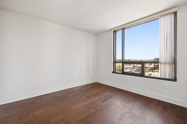 unfurnished room featuring baseboards and dark wood finished floors