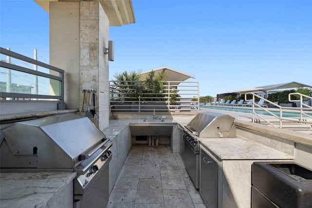 view of patio / terrace with a community pool, a grill, a balcony, and area for grilling