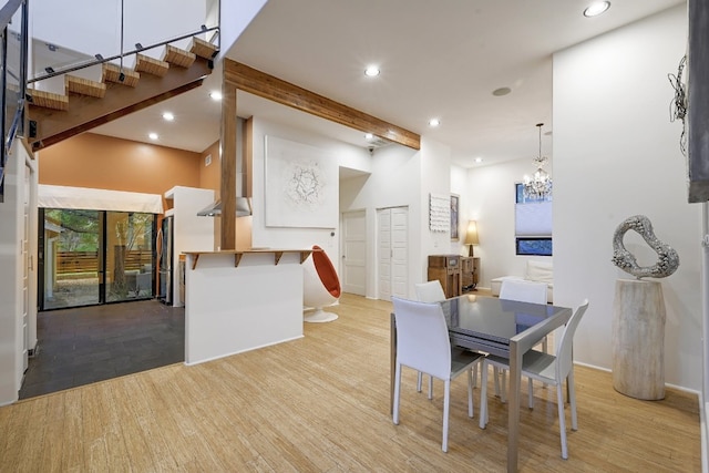 dining area with a towering ceiling, light hardwood / wood-style floors, and beamed ceiling