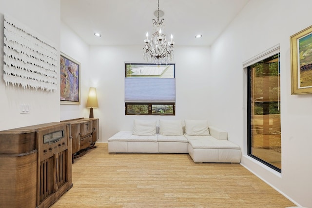 living room featuring light wood-type flooring, a notable chandelier, and plenty of natural light