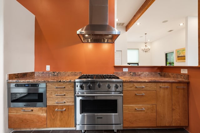 kitchen with wall chimney range hood, beamed ceiling, a chandelier, dark stone counters, and appliances with stainless steel finishes