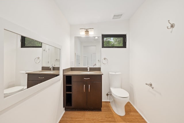 bathroom with hardwood / wood-style floors, lofted ceiling, vanity, and toilet