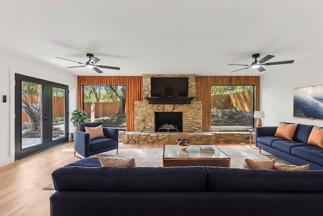 living room featuring a fireplace, french doors, light wood-type flooring, and ceiling fan