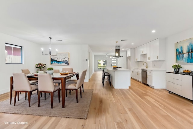 dining space featuring an inviting chandelier, sink, and light wood-type flooring