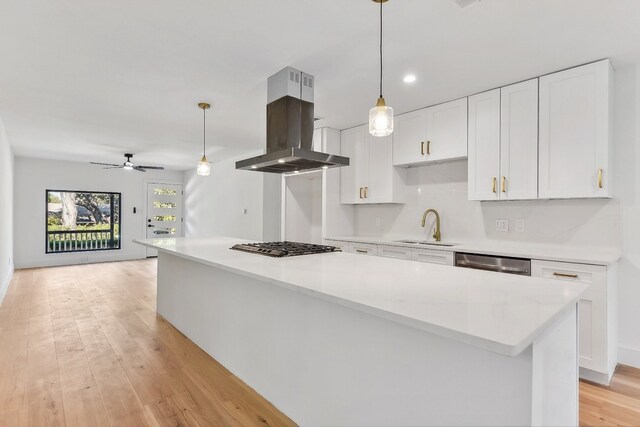 kitchen with white cabinets, a kitchen island, island range hood, pendant lighting, and sink