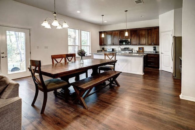 dining area with an inviting chandelier, sink, and dark hardwood / wood-style floors