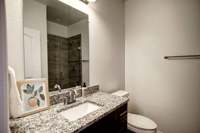 bathroom with vanity, a shower with door, and toilet