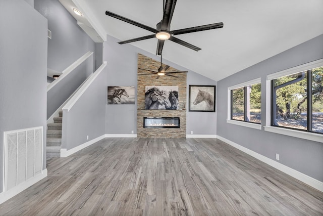 unfurnished living room with high vaulted ceiling, a fireplace, light hardwood / wood-style floors, and ceiling fan