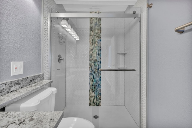 bathroom featuring a shower with door, vanity, and toilet