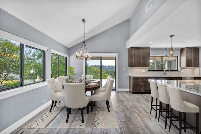 dining room featuring sink, light hardwood / wood-style floors, a notable chandelier, and a wealth of natural light