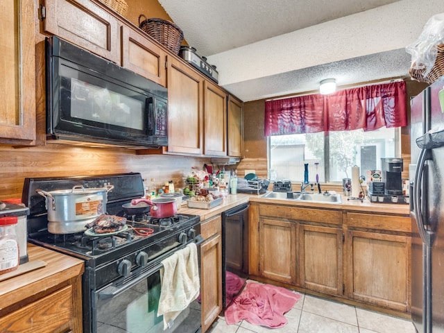 kitchen with black appliances, sink, light tile patterned floors, and a textured ceiling