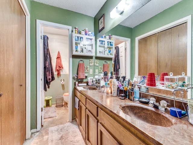 bathroom with a textured ceiling, vanity, and toilet