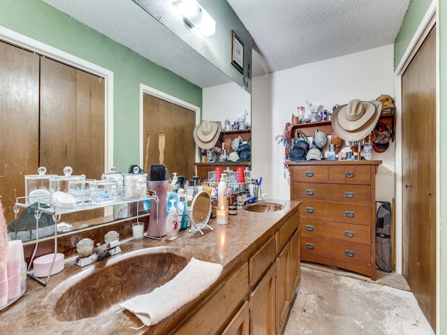 bathroom with concrete floors, vanity, and a textured ceiling