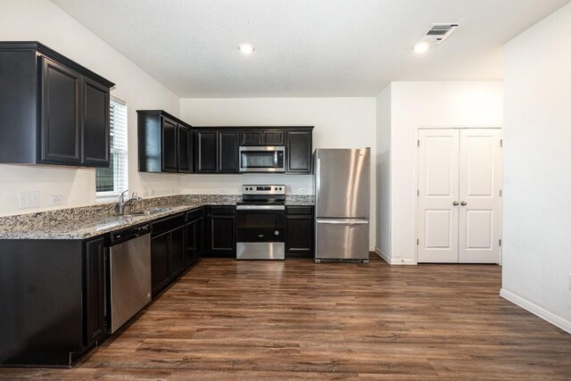 kitchen featuring light stone counters, stainless steel appliances, dark hardwood / wood-style floors, and sink