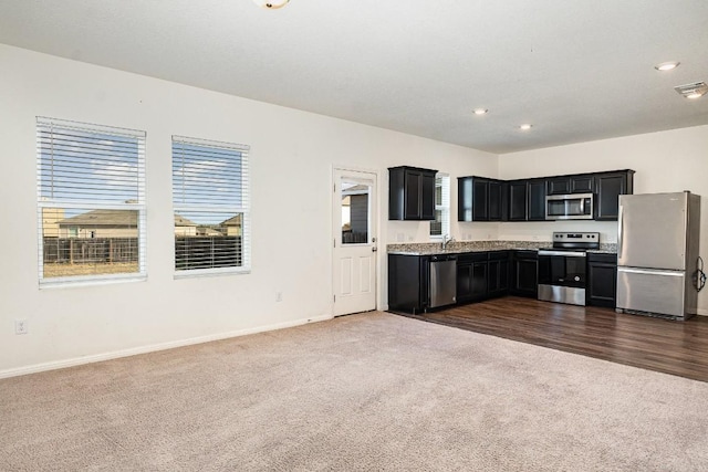 kitchen with dark cabinets, baseboards, light countertops, appliances with stainless steel finishes, and dark carpet