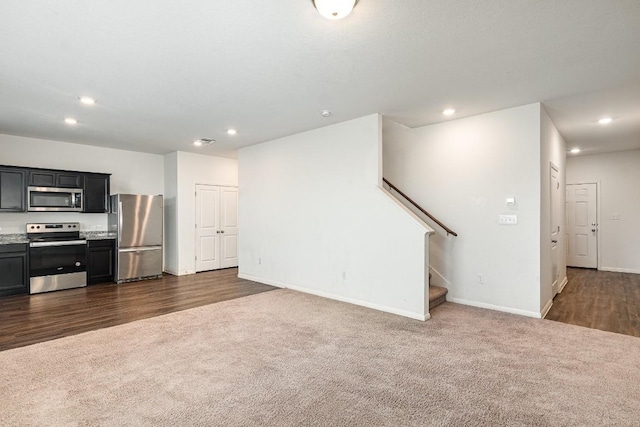 unfurnished living room with recessed lighting, visible vents, baseboards, stairway, and dark colored carpet