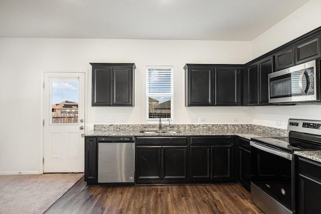 kitchen featuring dark cabinets, a wealth of natural light, stainless steel appliances, and a sink