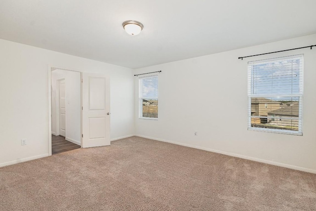 carpeted spare room featuring baseboards