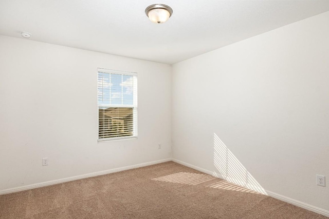 spare room featuring carpet floors and baseboards