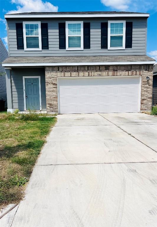 traditional home with an attached garage, a front lawn, concrete driveway, and brick siding