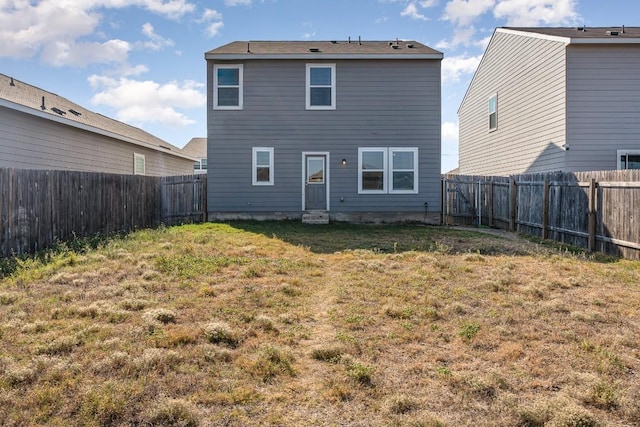 rear view of property with a fenced backyard and a yard