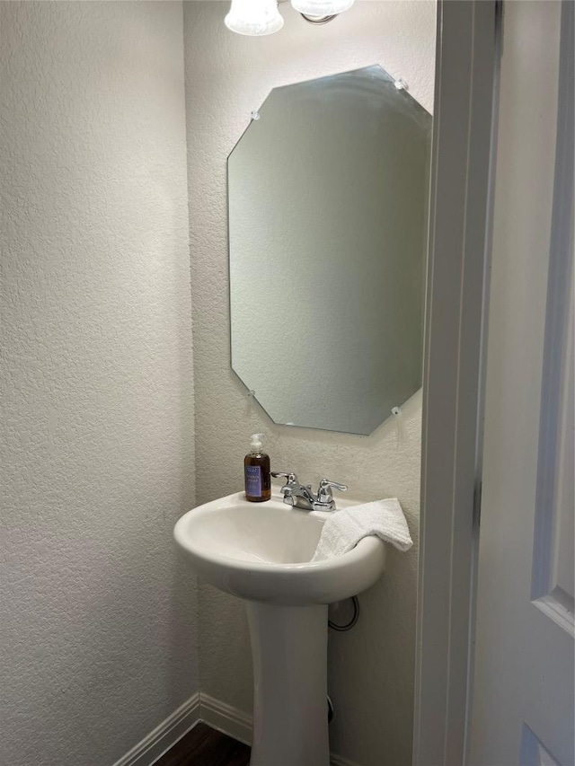 bathroom featuring a textured wall and baseboards