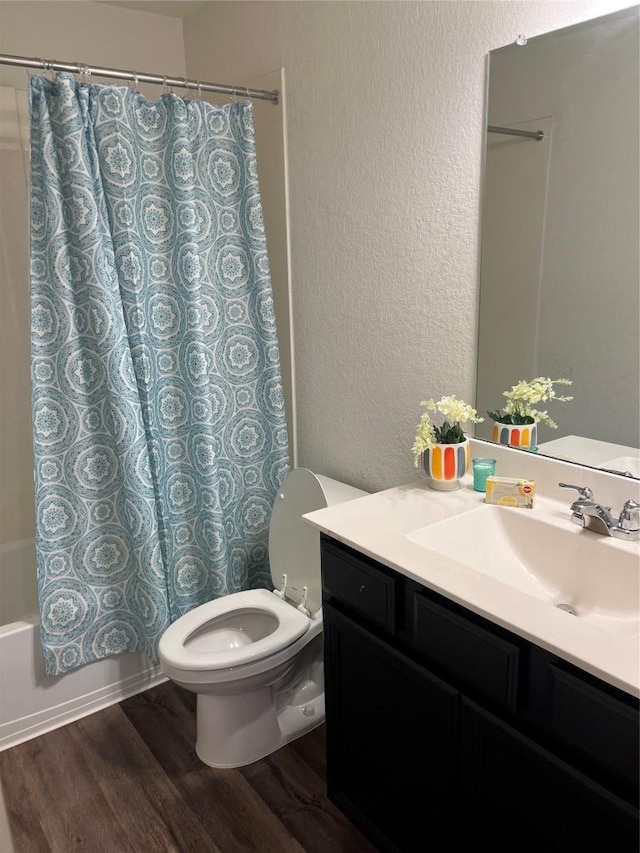 full bathroom with a textured wall, toilet, wood finished floors, vanity, and shower / bath combination with curtain